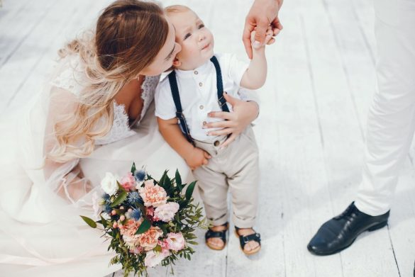 Mariée réconfortant un petit garçon en larmes lors d'une réception nécessitant de bonnes idees animations et baby-sitter enfants mariage.