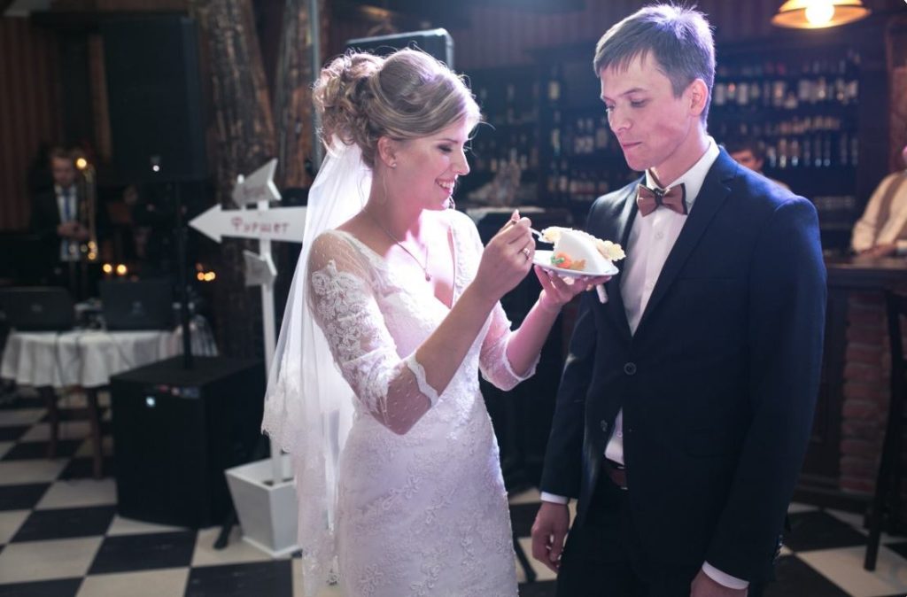 Mariés partageant une part de gâteau sur la piste de danse avant d'appliquer les astuces pour garder la piste de danse pleine mariage